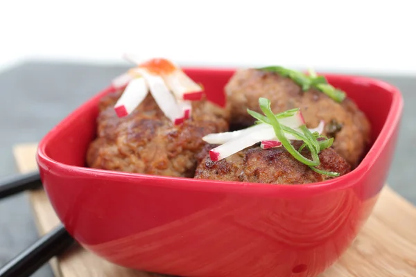 Three meatballs in a red bowl with condiments. — Stock Photo, Image