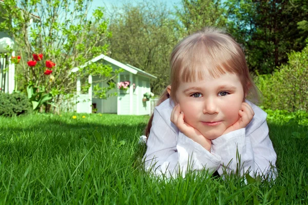 Nettes kleines Mädchen liegt auf grünem Gras — Stockfoto
