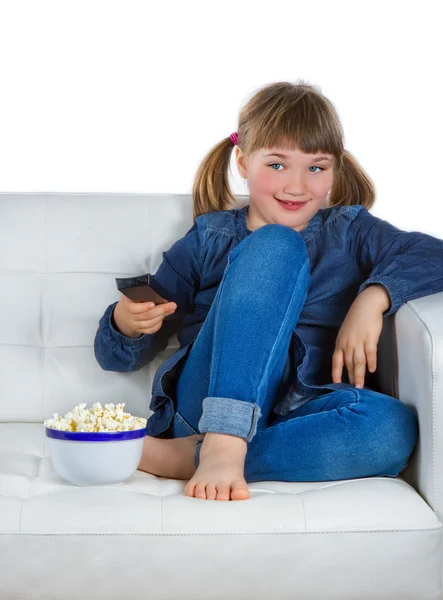 Menina sentada em um sofá assistindo TV — Fotografia de Stock