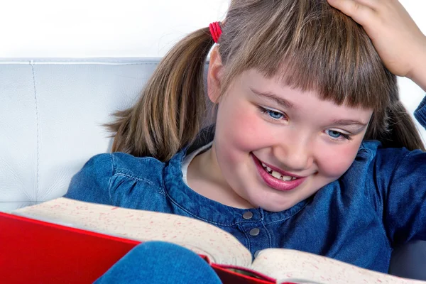 Menina sorrindo e lendo um livro — Fotografia de Stock