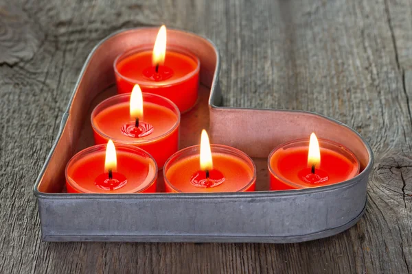 Velas rojas en una bandeja de lata en forma de corazón — Foto de Stock