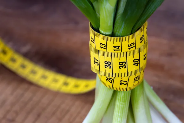 Grüne Zwiebeln mit gelbem Maßband — Stockfoto