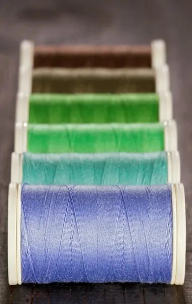 Green and blue spools of thread on dark background — Stock Photo, Image