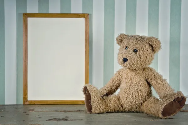 Viejo osito de peluche junto a un marco vacío — Foto de Stock