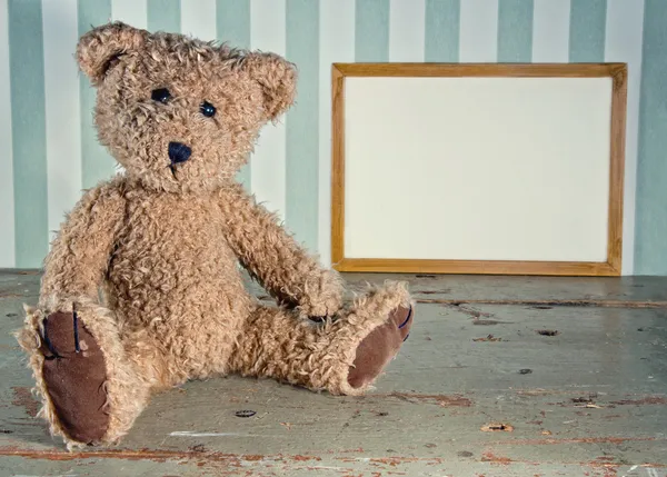 坐在旁边一个空的木制框架的古董玩具熊 — 图库照片