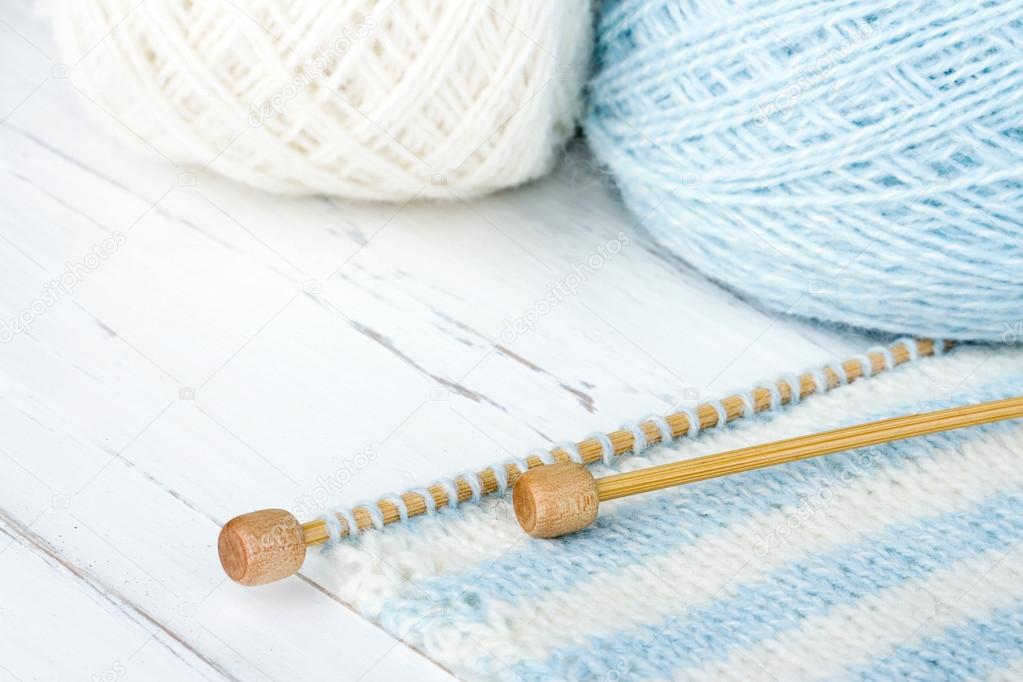 White and blue colored knitting on wooden background