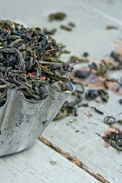 Dry green tea leaves in a rustic metal cupcake — Stock Photo, Image