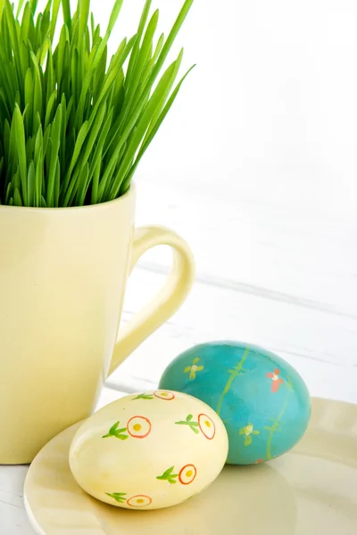 Due uova di Pasqua dipinte con una tazza di erba verde — Foto Stock