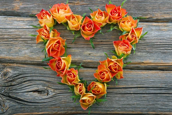 Roses in heart shape on wooden background — Stock Photo, Image