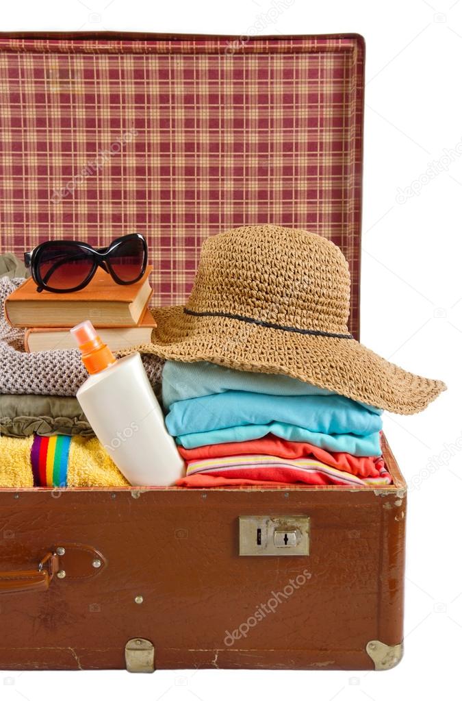 Vintage suitcase packed with clothes for beach vacation