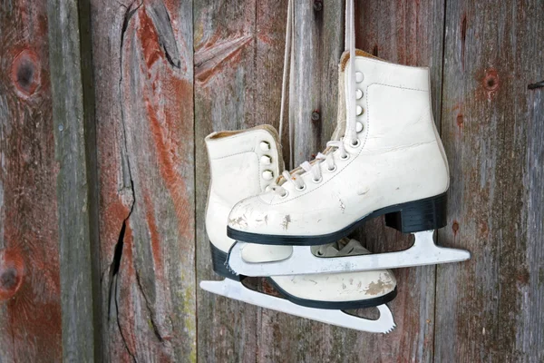 Oude schaatsen opknoping op een houten muur — Stockfoto