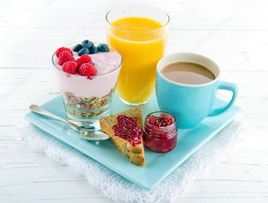 Breakfast with yoghurt, berries, juice, toast and coffee