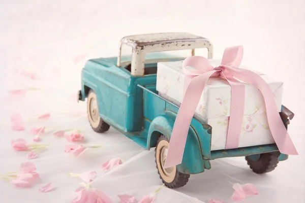 Antique toy truck carrying a gift box with pink ribbon — Stock Photo, Image