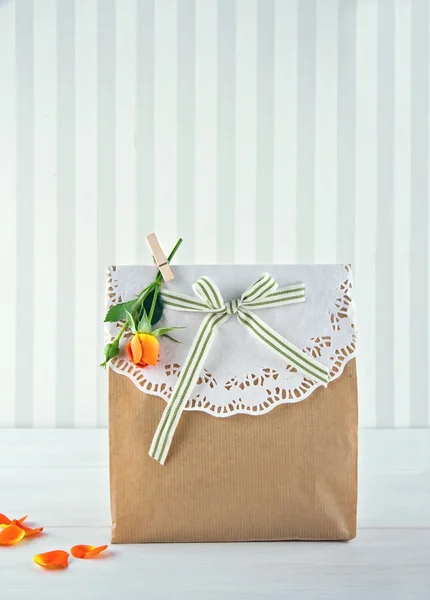 Geschenktüte aus braunem Papier dekoriert und gelbe Rose — Stockfoto