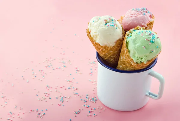 Conos de helado con salpicaduras sobre fondo rosa — Foto de Stock