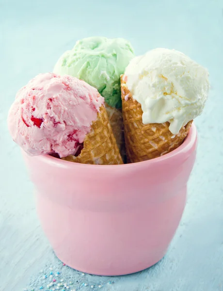 Três cones de sorvete em um frasco rosa no fundo azul — Fotografia de Stock