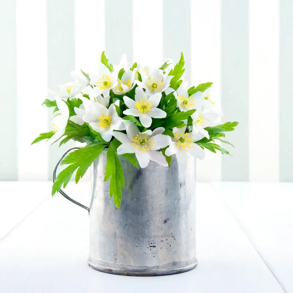 Våren vilda blommor i en metall kopp på vintage bakgrund — Stockfoto