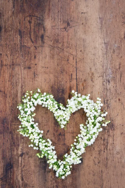 Herzförmiger Blumenkranz auf rustikalem Hintergrund — Stockfoto