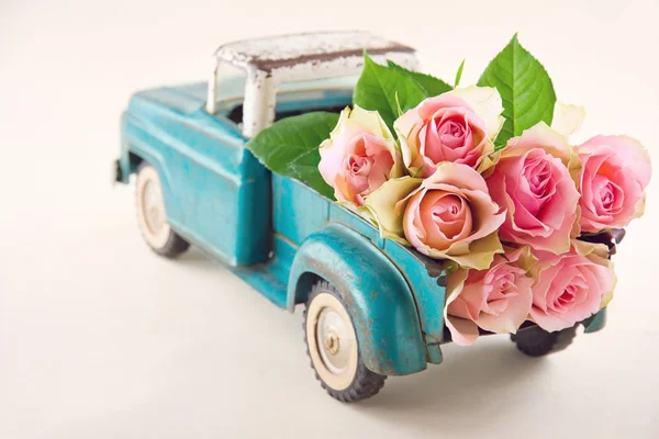 Antikes Spielzeugauto mit rosa Rosen — Stockfoto