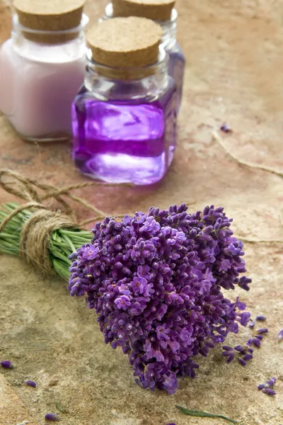 Bouquet of fresh purple flowers and bottles of soap and lotion — Stock Photo, Image