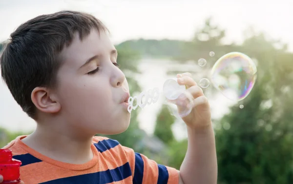 Jeune garçon soufflant bulles de savon — Photo