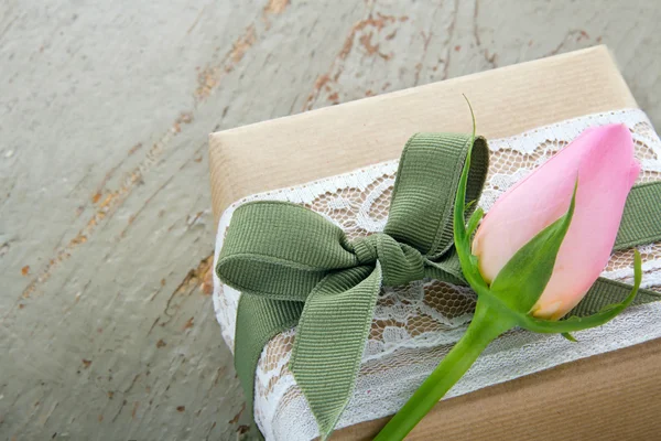 Caja de regalo envuelta en papel marrón con rosa — Foto de Stock