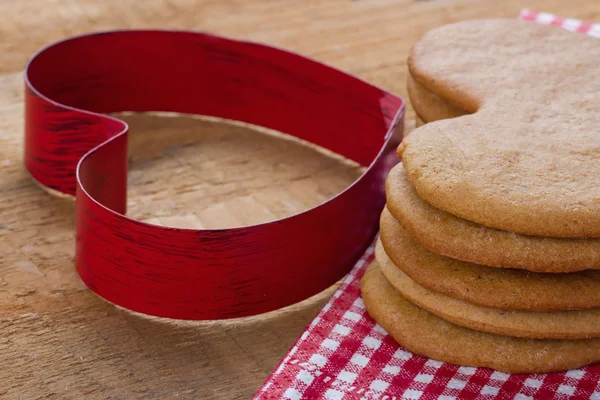 Röd cookie cutter och hembakade pepparkakor — Stockfoto