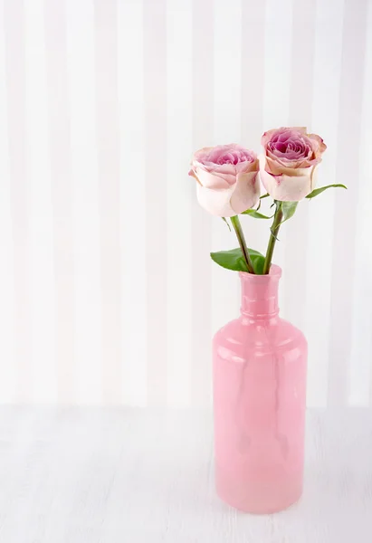 在一个木制的背景上的玻璃瓶的粉红玫瑰 — 图库照片