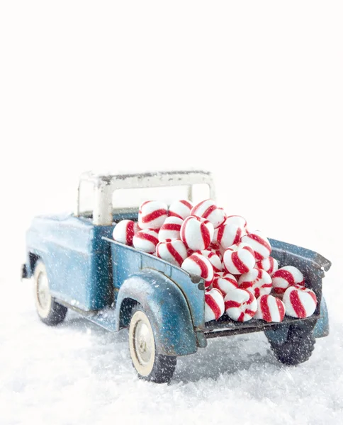 Blue toy truck carrying striped peppermint candy — Stock Photo, Image