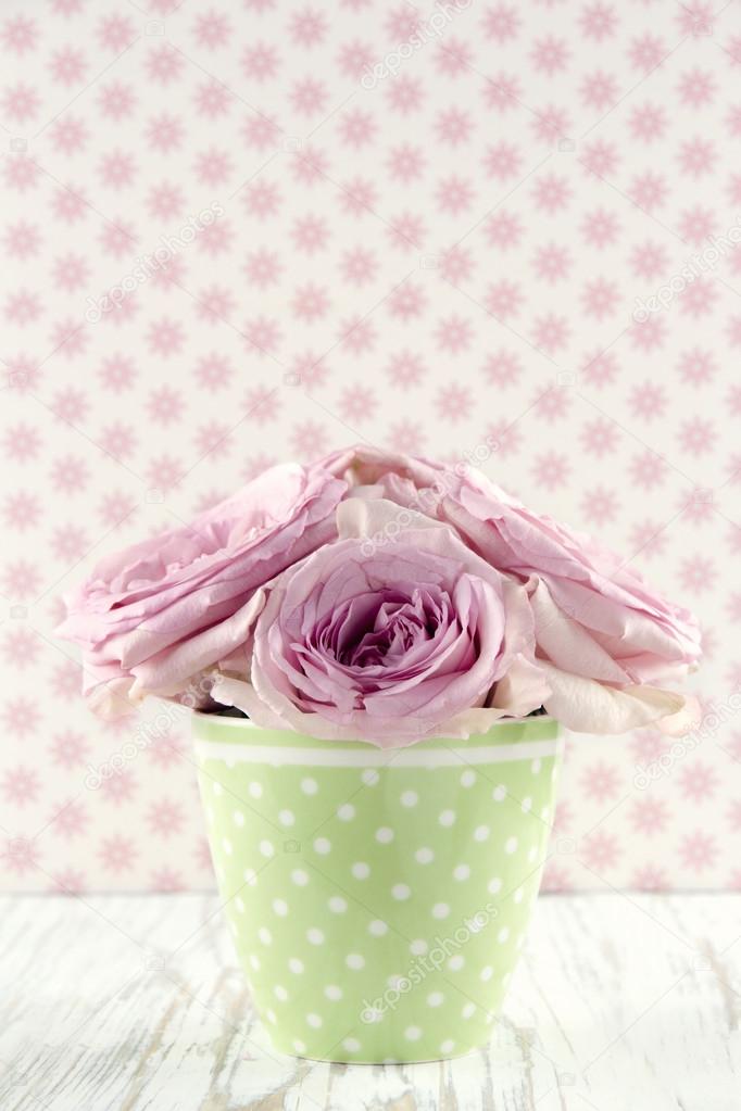 Flowers in a green polkadot vase on vintage wooden background