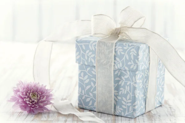 Gift box tied up with white ribbon and pink flower — Stock Photo, Image