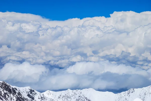 俯瞰多雪的岩石山脉 浓密的波浪形云彩笼罩了山谷 蓝天帕米尔高山 — 图库照片