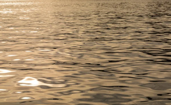 Suyun yüzeyinde güneş parlıyor. Denizin yüzeyindeki sonsuz ışık..