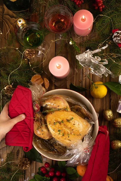 Baked Christmas turkey in a red dish is placed on the festive table. Chicken is appetizing and delicious. red towels and a glove for the kitchen.