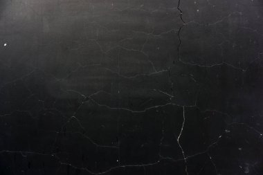 Çatlak yüzeyi olan siyah bir arka plan. Ağ şeklinde çatlaklar var. Çimento temel dokusu.