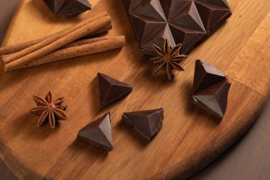 Kara acı çikolata parçalara ayrılır. Tarçın çubuklarıyla süslenmiş..