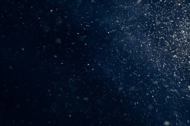 Koyu mavi arka planda sürerken yavaş çekimde gerçek kar yağıyor. Grafik düzenleyicilerdeki tasarım için kar dokusu