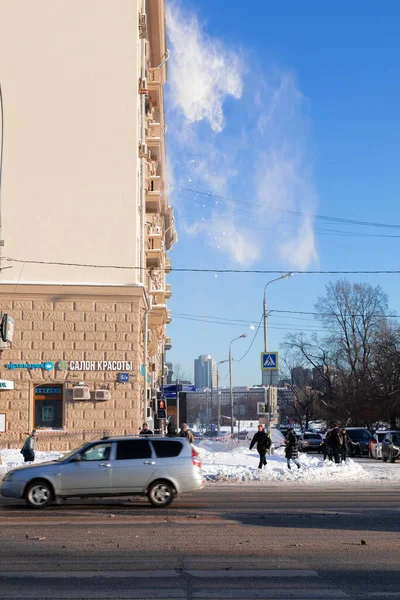 15.02.2021, Россия, Москва. Уборка крыши снега. Снег падает на голубое небо. — стоковое фото