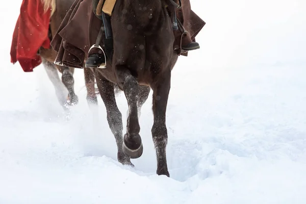 A group of riders on horseback crosses the snowy plain of the field at a gallop — Stock Photo, Image