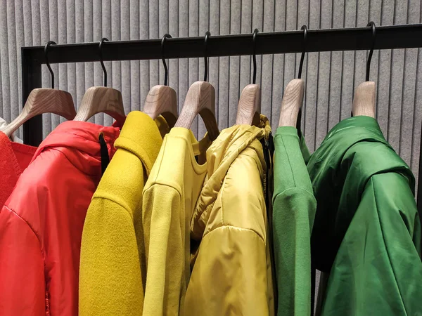 Een heldere lente collectie dameskleding hangt aan hangers in de winkel. Stockafbeelding