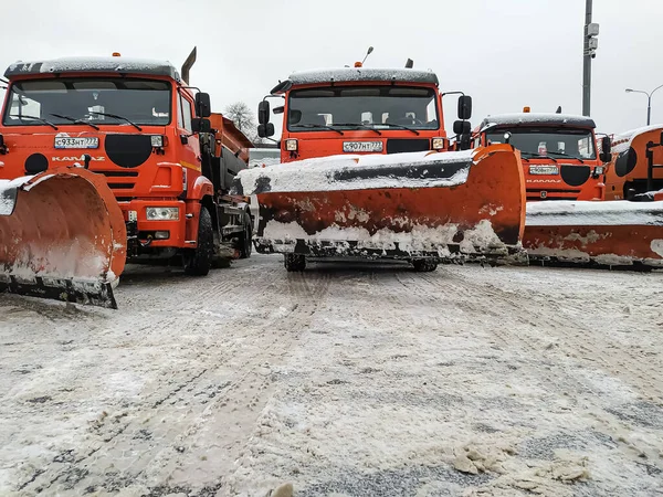 Sneeuwploegen met een ploeg om wegen vrij te maken. Auto 's staan geparkeerd te wachten op werk en sneeuw Rechtenvrije Stockafbeeldingen