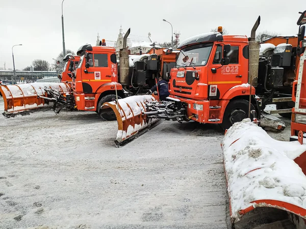 Aratri da neve con un aratro per liberare le strade. Le auto sono parcheggiate in attesa di lavoro e nevicate Immagini Stock Royalty Free