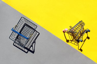 Minyatür bir alışveriş arabası ve alışveriş arabası sarı ve gri arka planda yatar..