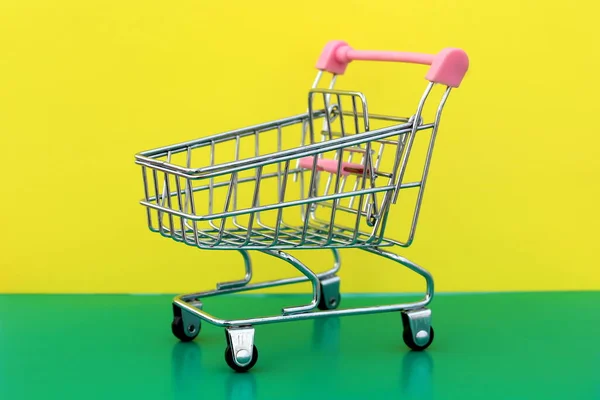 Miniature Shopping Cart Stands Green Yellow Background — Stock Photo, Image