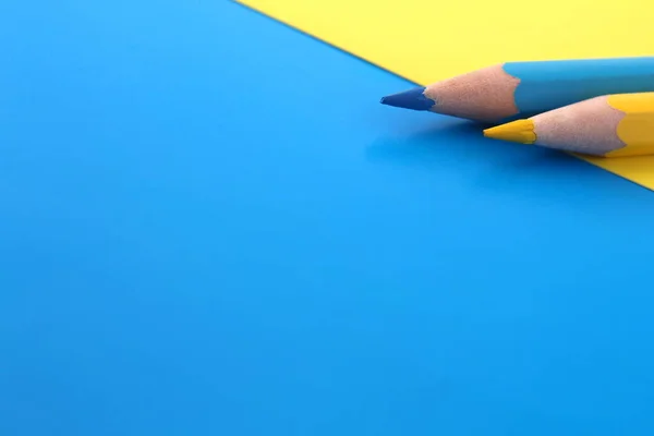 Modrém Žlutém Pozadí Leží Dvě Tužky Stejné Barvy Současně Prostorem — Stock fotografie