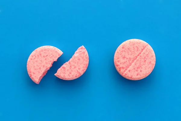 Egy Rózsaszín Egész Tabletta Fekszik Egy Törött Mellett Kék Alapon — Stock Fotó