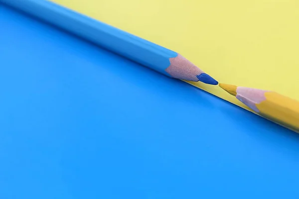 Een Blauwe Gele Achtergrond Twee Potloden Van Dezelfde Kleur Liggen Stockfoto