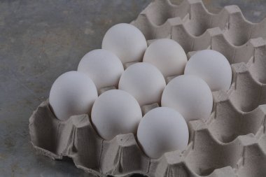 Chicken eggs close-up in a corton box on a gray stand