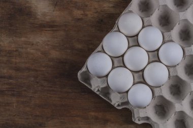 Tavuklu yumurtalar, ahşap bir masada gri bir Corton kutunun içinde.