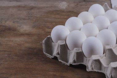 Tavuklu yumurtalar, ahşap bir masada gri bir Corton kutunun içinde.